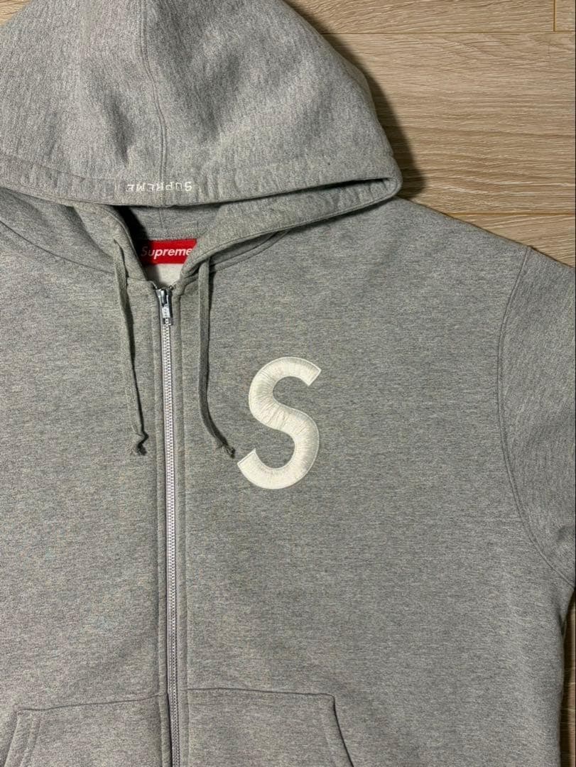 Sの刺繍が特徴のグレーのフルジップパーカー。